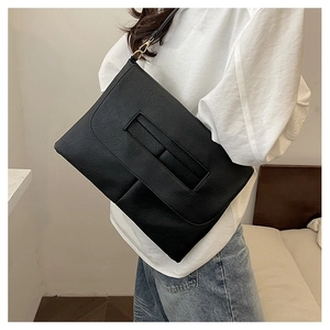 Detail einer schwarzen Leder-Schultertasche mit Goldmetallschnallen und Klappendesign