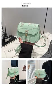 Détail d'un sac selle vert menthe avec broderie florale délicate et fermoir en métal doré