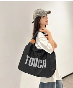 Dettaglio borsa tote in nylon nero con stampa TOUCH e rinforzi in pelle sui manici