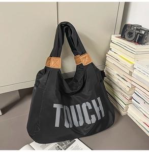 Dettaglio della borsa tote in nylon nero con scritta TOUCH grigia e dettagli in cuoio