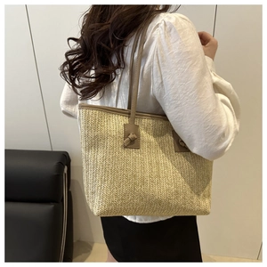 Détail du sac cabas en paille tissée avec anses en cuir marron et nœuds décoratifs