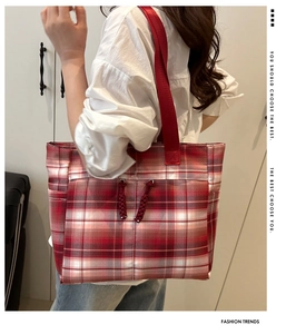 Detail view of red plaid canvas tote bag with decorative drawstrings and side pocket
