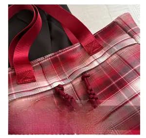 Detail of red checkered tote with a woven zipper pull and durable nylon handles