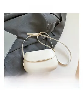 Detail shot of the off-white PU saddle bag featuring fine texture and smooth magnetic flap
