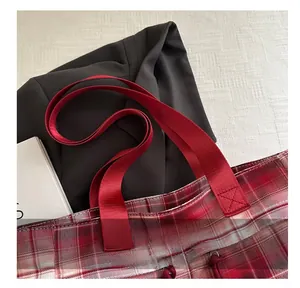 Detail of red checkered canvas tote with reinforced handles and cross-stitched webbing