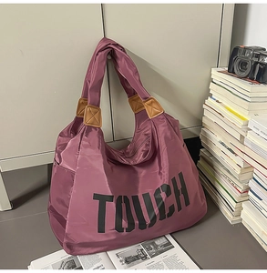 Dettaglio della borsa tote in nylon viola con scritta TOUCH e inserti in pelle marrone