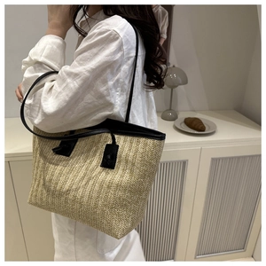 Détail du sac cabas en paille avec poignées en cuir noir et motif de tissage texturé