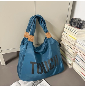 Dettaglio della borsa tote in nylon blu con scritta TOUCH e inserti in pelle marrone