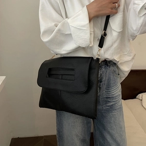 Minimalistische schwarze Umhängetasche aus Leder mit Tragegriff am Model gezeigt