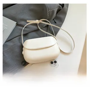 Detailed comparison of the compact cream saddle bag next to a smartphone for size reference