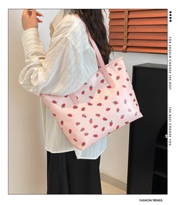 Sac fourre-tout rose à motif fraises porté à l'épaule sur une chemise claire