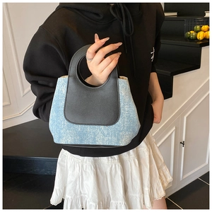 Detail van tweekleurige emmertas van blauwe denim en zwart leer met kleine strass