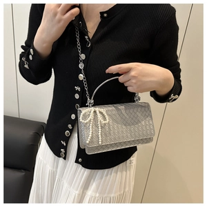 Detailed view of silver woven shoulder bag with pearl bow and metal handle