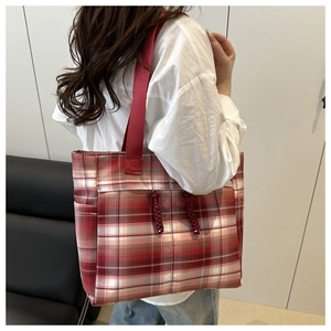 Détail du sac cabas à carreaux rouges avec breloques à franges et toile résistante