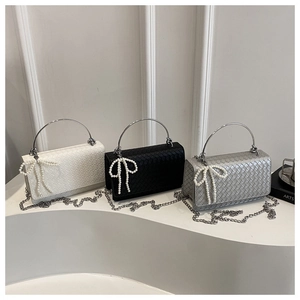 Detalle de mini bolsos de hombro en cuero trenzado con colgantes de lazo de perlas y cadena