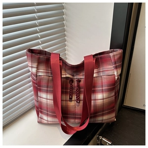Detail view of red plaid tote bag with sturdy nylon straps and front zipper pockets