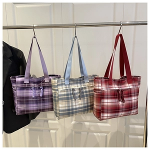 Three plaid tote bags in purple, blue, and red hanging on a display stand