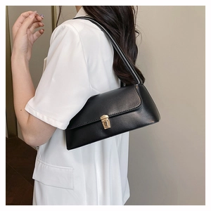 Detail of a black minimalist underarm bag with gold buckle on a white blazer background