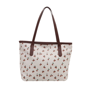 Stylish tote bag with cherry print and dark brown handles on a clean white background