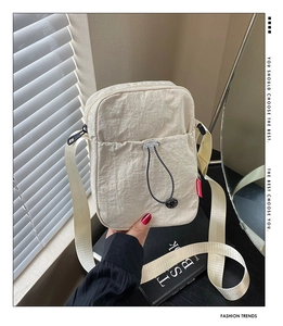 Détail du sac bandoulière en nylon beige avec poche avant à cordon et logo
