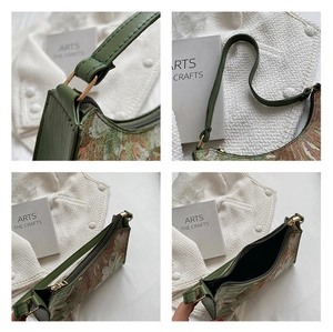 Detail view of floral tapestry shoulder bag with green leather strap and gold hardware