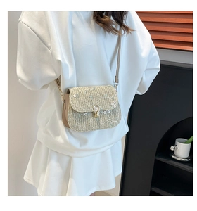 Détail d'un sac selle en paille avec broderies florales, sequins et fermoir doré