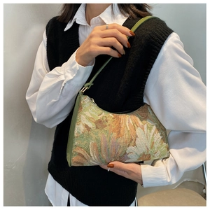 Detail of floral tapestry underarm bag with vintage hobo shape and green strap