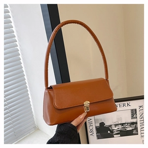 Close-up of caramel leather shoulder bag featuring a vintage golden metal clasp buckle