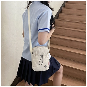 Détail d'un sac bandoulière en nylon crème avec cordon de serrage et sangle réglable