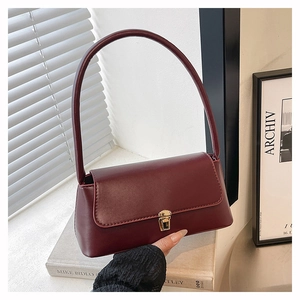 Detail of burgundy shoulder bag with golden twist lock on minimalist books