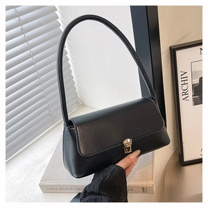 Detail of elegant black baguette bag with vintage gold metal clasp and matte leather finish