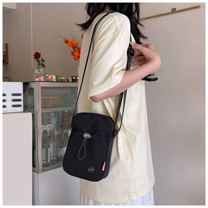 Détail du sac bandoulière en nylon noir avec poche à cordon et étiquette de mode