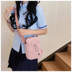 Sac bandoulière en nylon rose avec poche à cordon et étiquette mode porté par un modèle