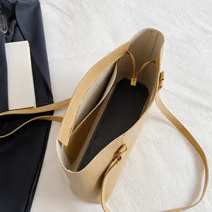 Detail view of the spacious inner compartment and side pocket of this beige tote bag