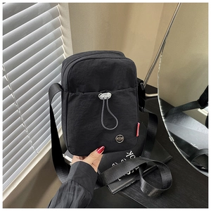 Détail de sac bandoulière en nylon noir avec poche à cordon et sangle réglable en tissu