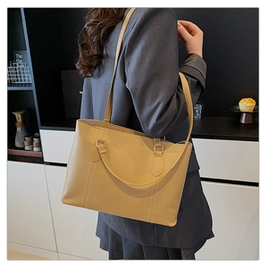 Close-up of beige tote bag with vertical stitching details and sleek leather handles