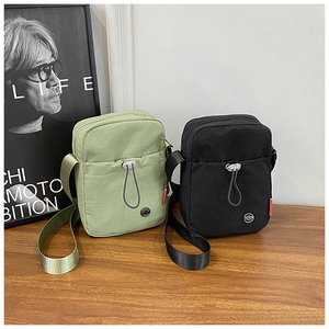 Gros plan de sacs à bandoulière en nylon minimalistes vert et noir sur table en bois