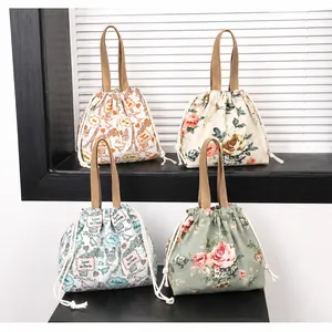 Détail de quatre sacs seaux en toile fleurie avec cordon de serrage en vert sauge