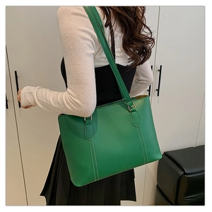 Detail view of large green tote bag showing side-wear effect and white stitching seams