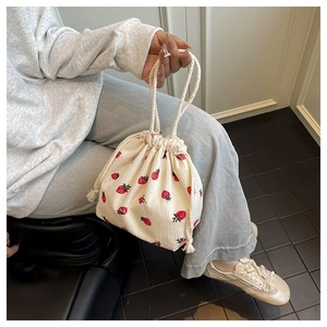 Detail der weißen Cord-Beuteltasche mit Erdbeerdruck und weichem Griff für junge Frauen