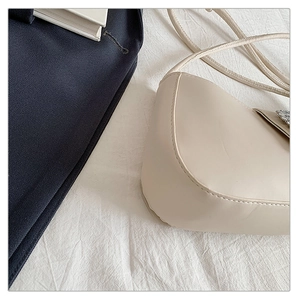 Détail d'un sac bandoulière demi-lune blanc cassé avec ornements floraux argentés