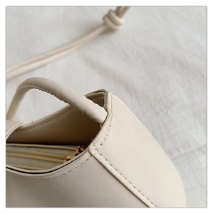 Détails des coutures et de la fermeture éclair du sac à bandoulière en cuir blanc cassé