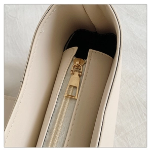 Détail de la fermeture éclair en métal doré sur un sac à bandoulière en cuir beige