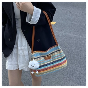Detail of colorful woven striped tote bag with leather straps and cloud charm