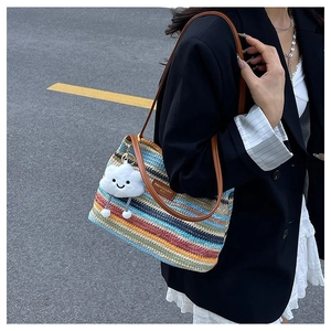 Detail of colorful woven tote with leather straps and a cute cloud charm accessory