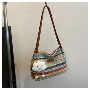 Detail of colorful woven straw tote bag featuring leather straps and a plush cloud charm