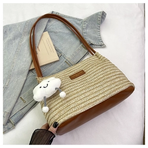 Detail of woven straw tote bag with brown leather base and cute cloud plush charm