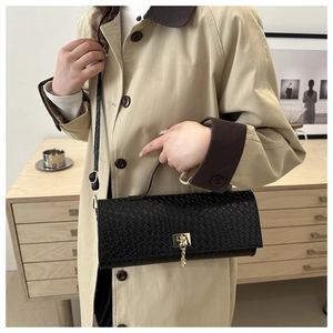 Detalle de bolso negro con textura de cocodrilo y elegante cierre giratorio dorado