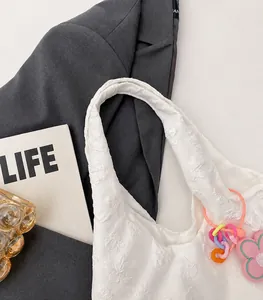 Detail of white floral embroidered tote bag featuring textured 3D flowers and soft handles