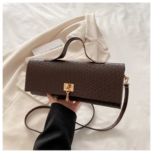Detail of dark brown woven texture handbag with elegant gold square lock buckle